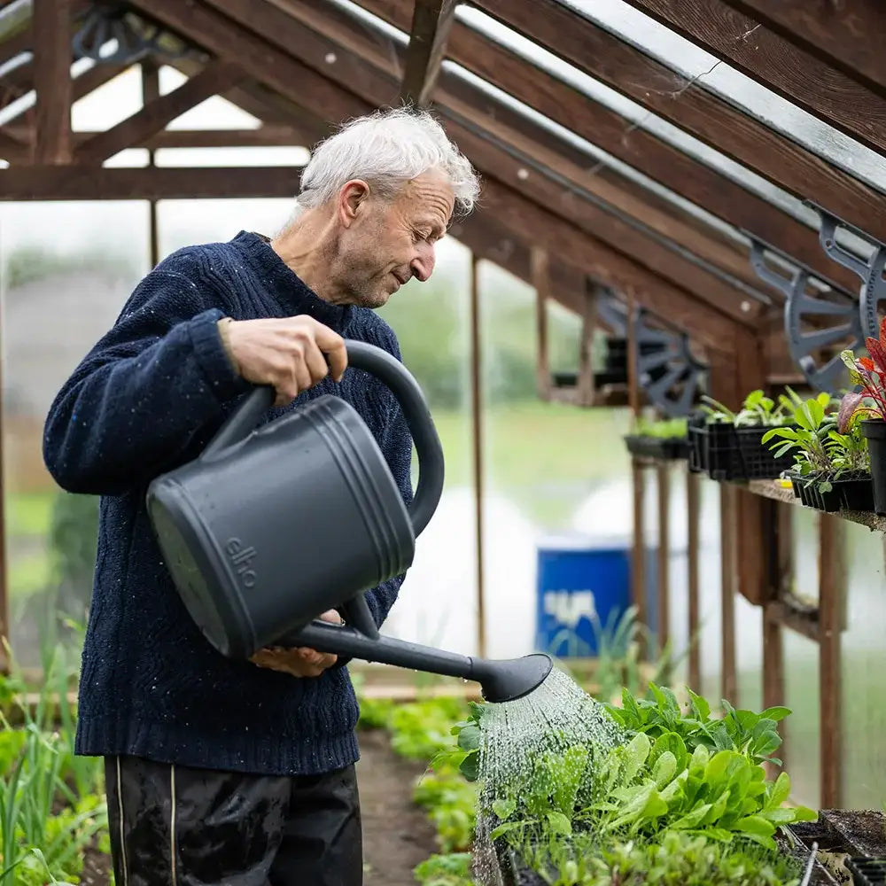 woman watering plastic plant Recycled plastic watering can – anthracite – Charles Dowding